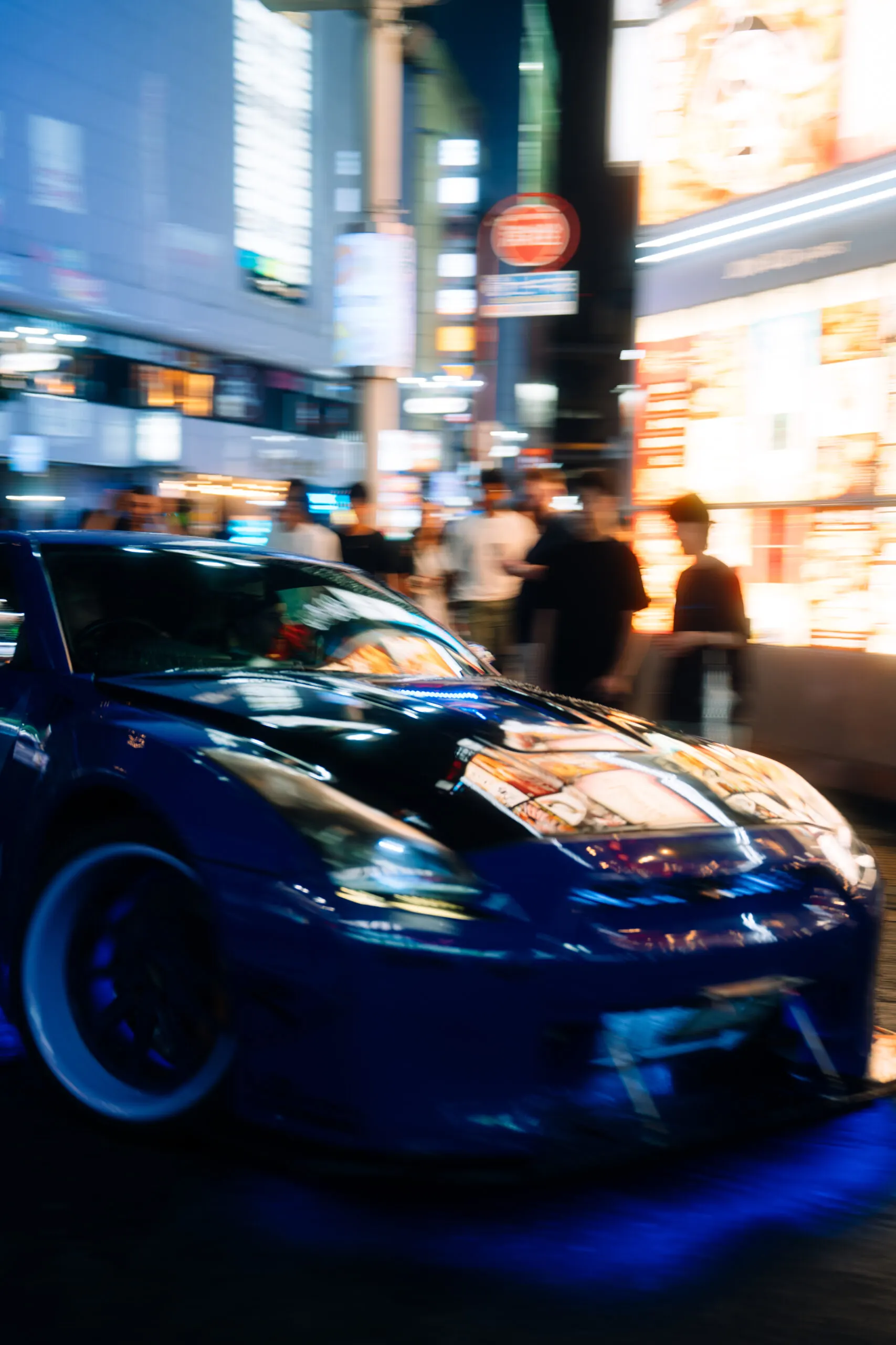 Blue sports car in a busy Shinjuku street
