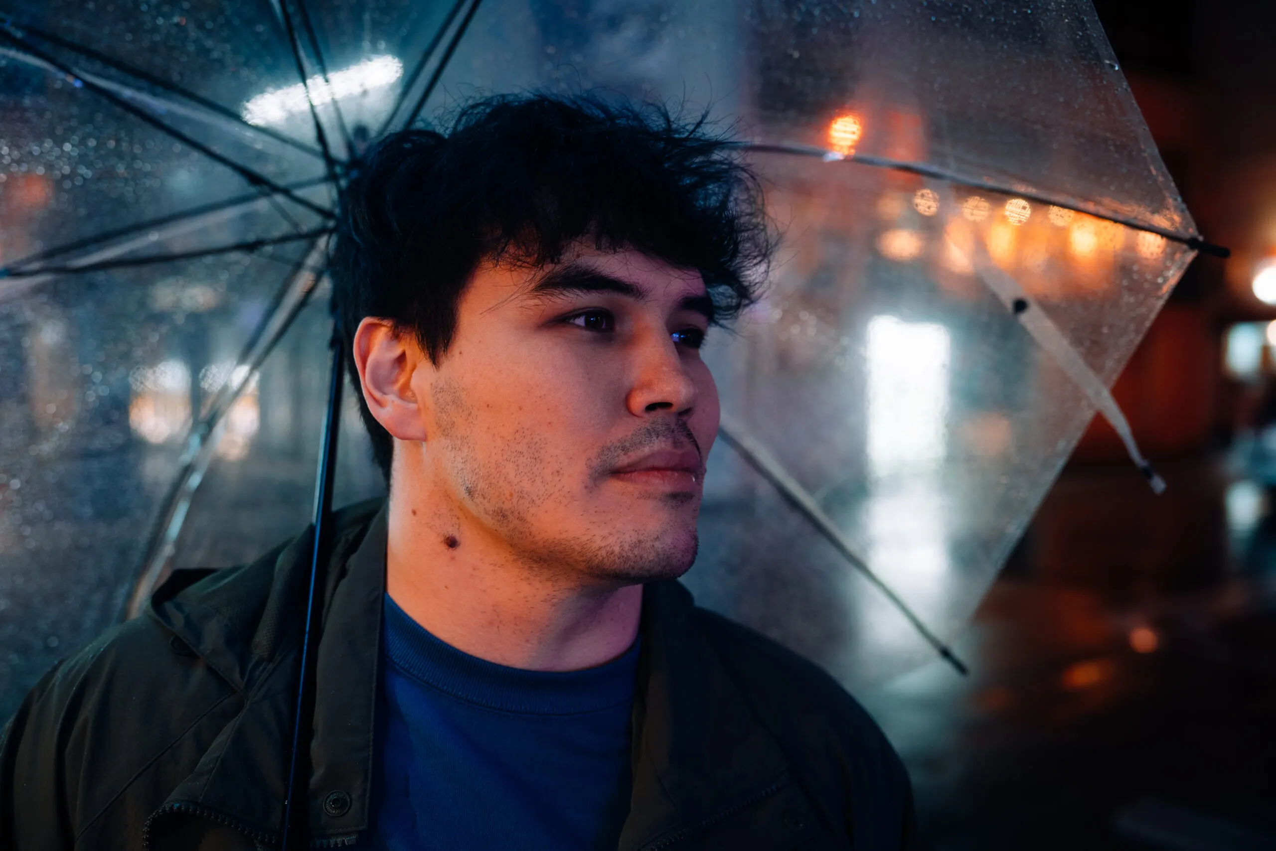 Young man under an umbrella in the rain at night