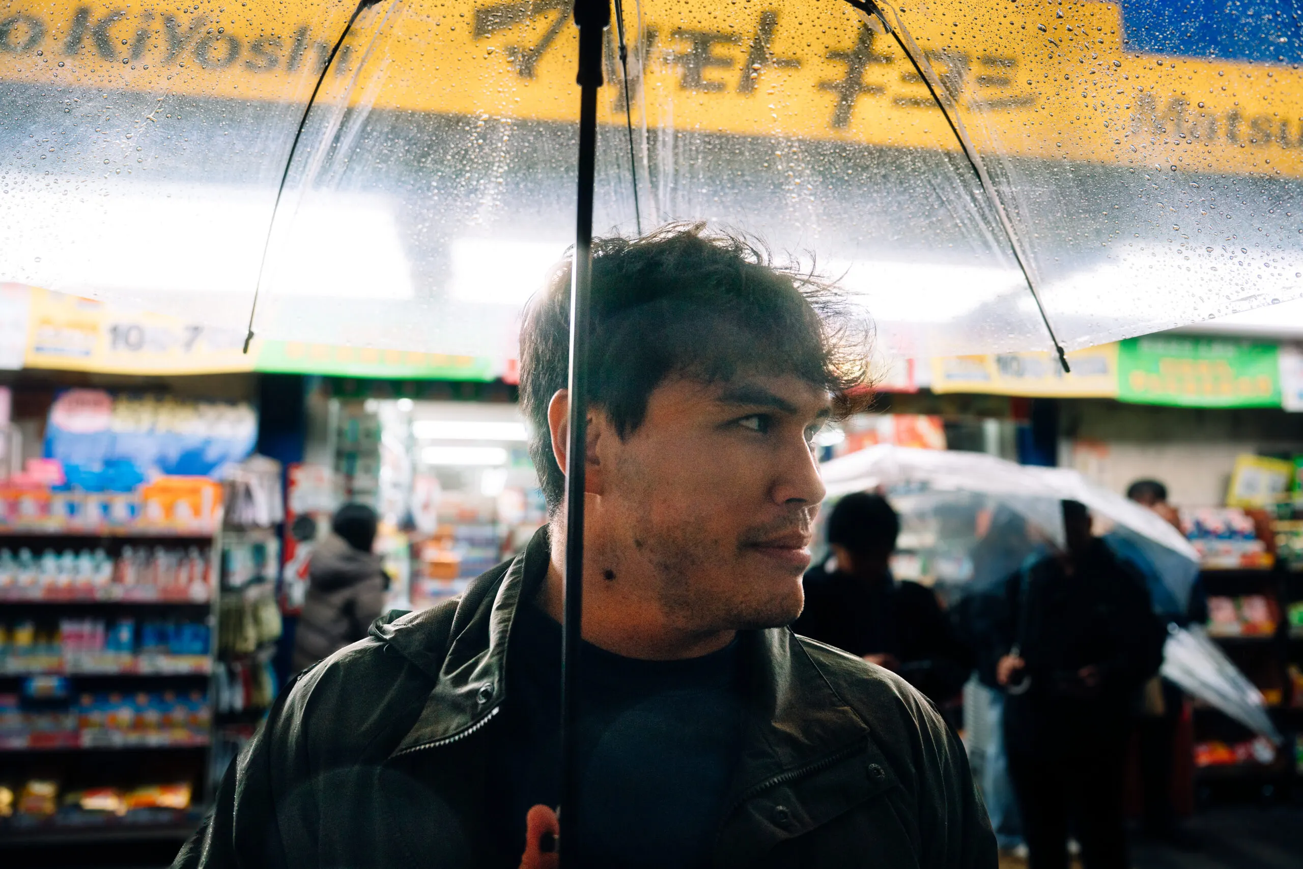 Man with umbrella in front of a convenience store