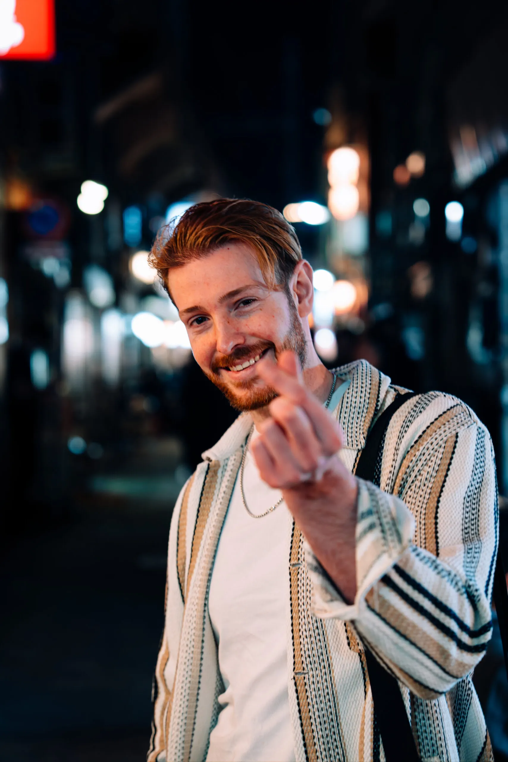 Smiling man making a finger heart at night
