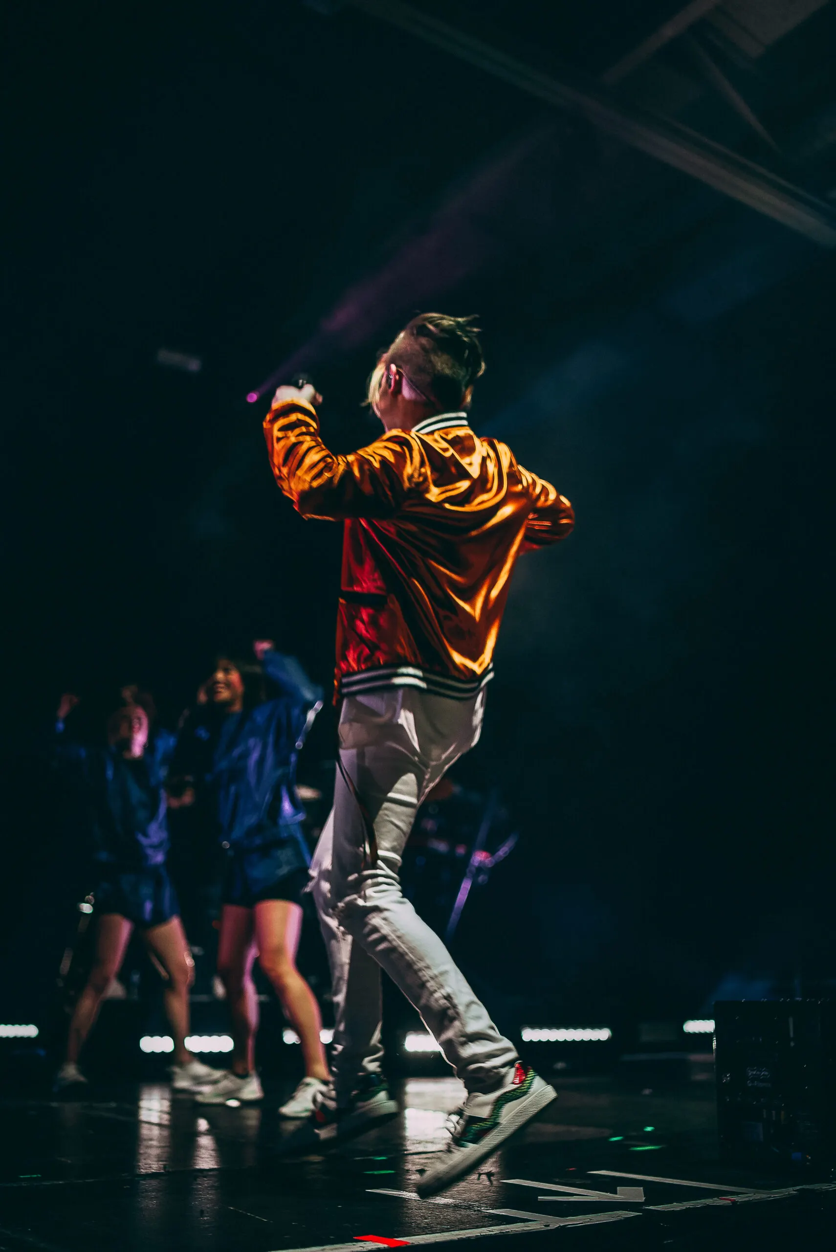 Performer on stage with dancers in dramatic light